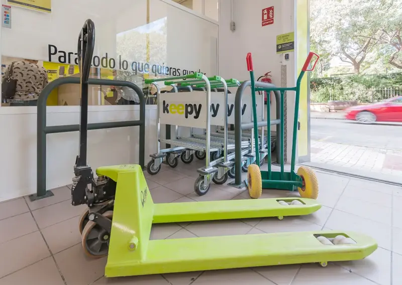 Carros de transporte y transpaleta junto al escaparate de la oficina de Keepy Estepona