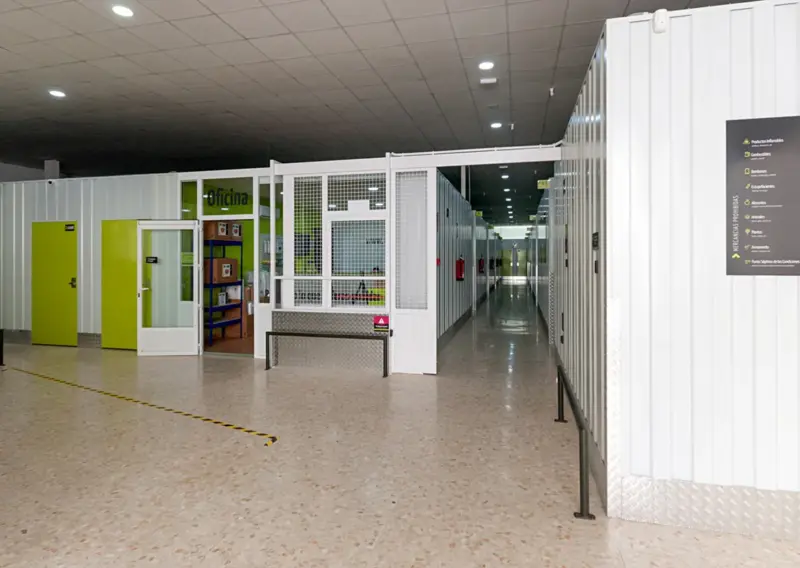 Pasillo interior con acceso a la oficina y señalética de servicios en Keepy Ciudad Jardín, Málaga