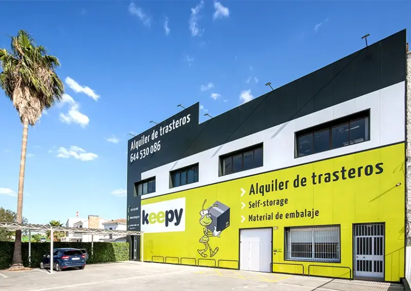 Fachada del centro Keepy de La Huertecilla, Málaga, con palmeras y el rótulo de alquiler de trasteros