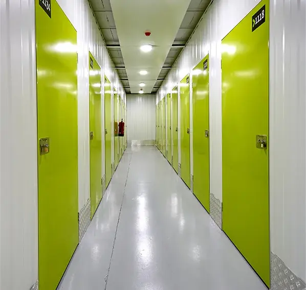 Pasillo largo de trasteros con puertas verdes numeradas en Keepy La Huertecilla, Málaga
