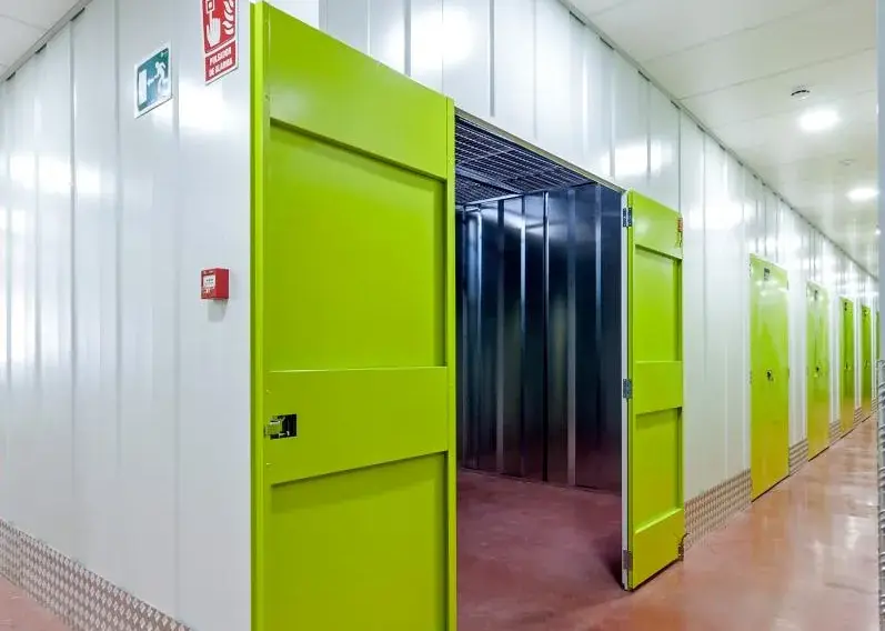Puerta verde de trastero abierta en un pasillo de suelo rojo del centro Keepy de Marbella
