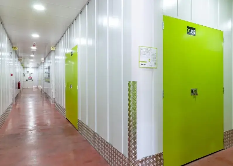 Pasillo de trasteros con una puerta verde abierta al fondo en el centro Keepy de Marbella
