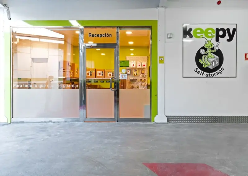 Puerta acristalada de recepción junto al rótulo Keepy self-storage en el centro de Mijas