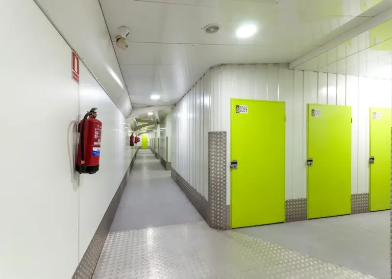 Pasillo de trasteros con puertas verdes y extintor en el centro Keepy de Mijas