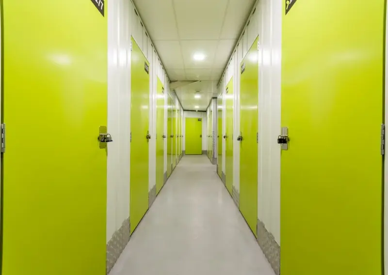 Pasillo largo con puertas verdes de trastero a ambos lados en el centro Keepy de Mijas